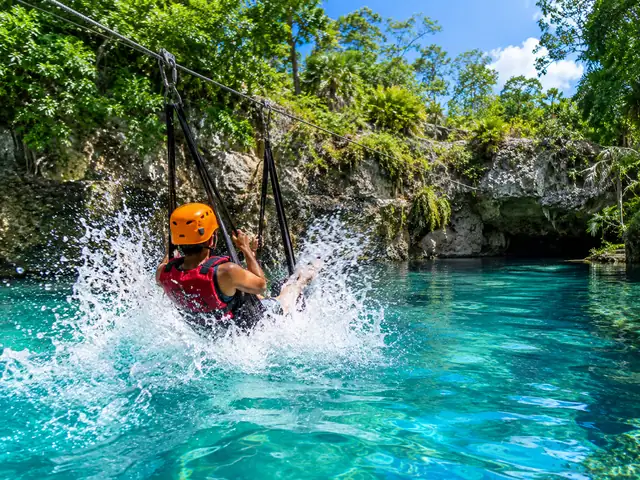 Un passager sur une tyrolienne en hamac atterrit dans un cenote turquoise