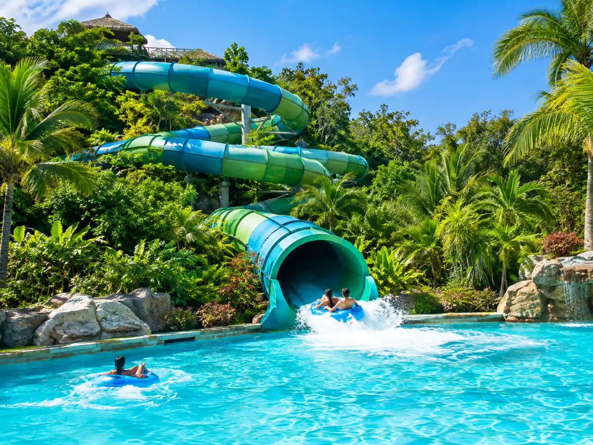 Toboggan géant se terminant dans une piscine à vagues turquoise en pleine jungle