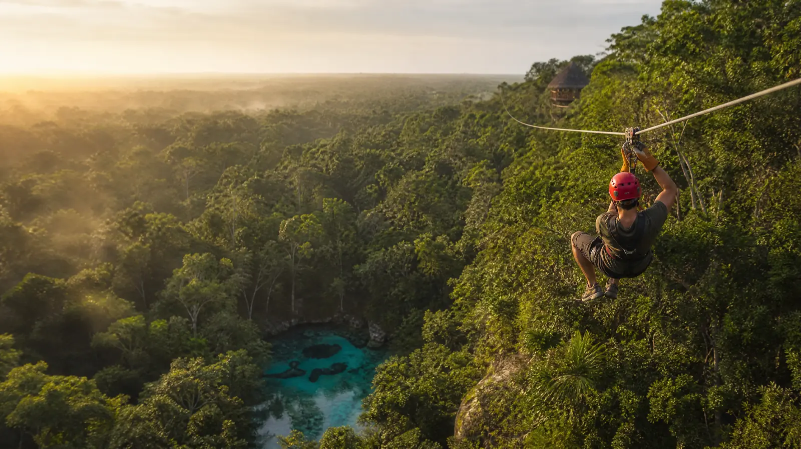 Personne en tyrolienne survolant la canopée de la jungle de la Riviera Maya
